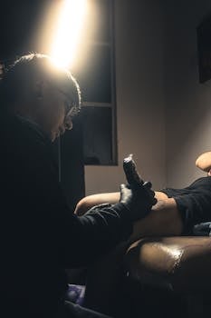 An artist tattooing a client in a dimly lit studio, capturing the focus and precision of the process.