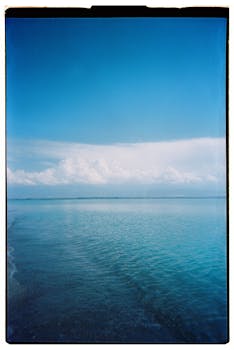 A serene view of a lake in Kyrgyzstan with a vast blue sky and calm waters.