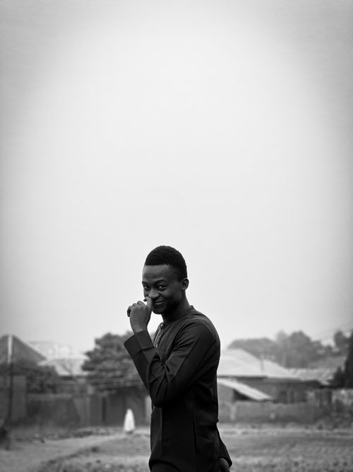 Free A young man poses outdoors with a thoughtful smile, captured in a black and white portrait. Stock Photo