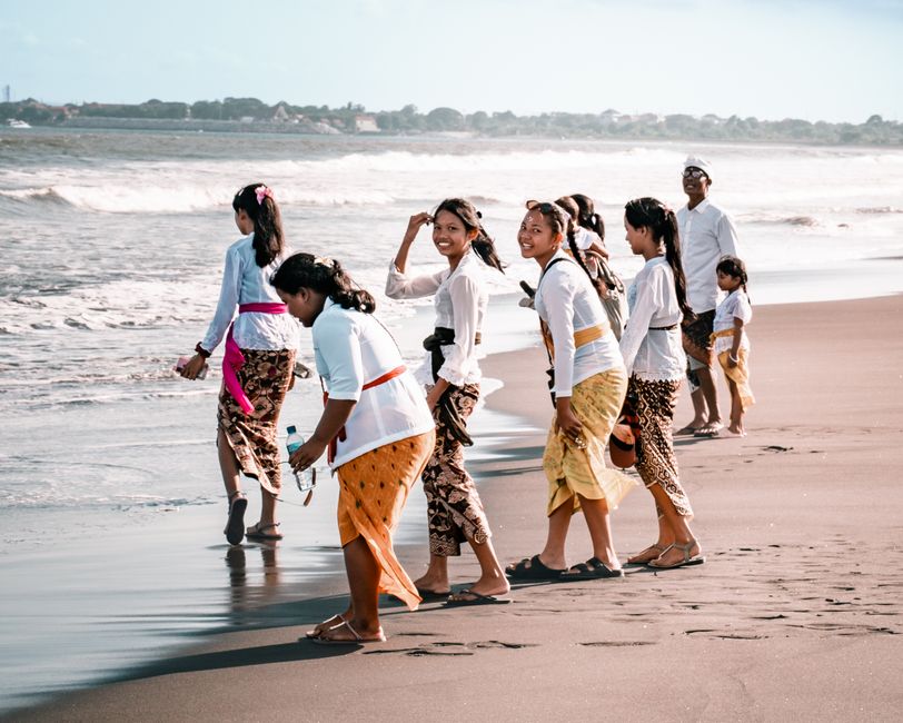 A group of people in traditional clothing enjoying a sunny day on a beach.