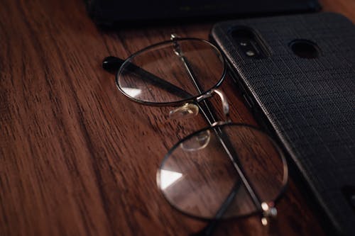 Photo Of Eyeglasses Beside Smart Phone