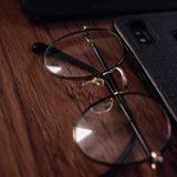 Smartphone and eyeglasses resting on a wooden table, close-up view.