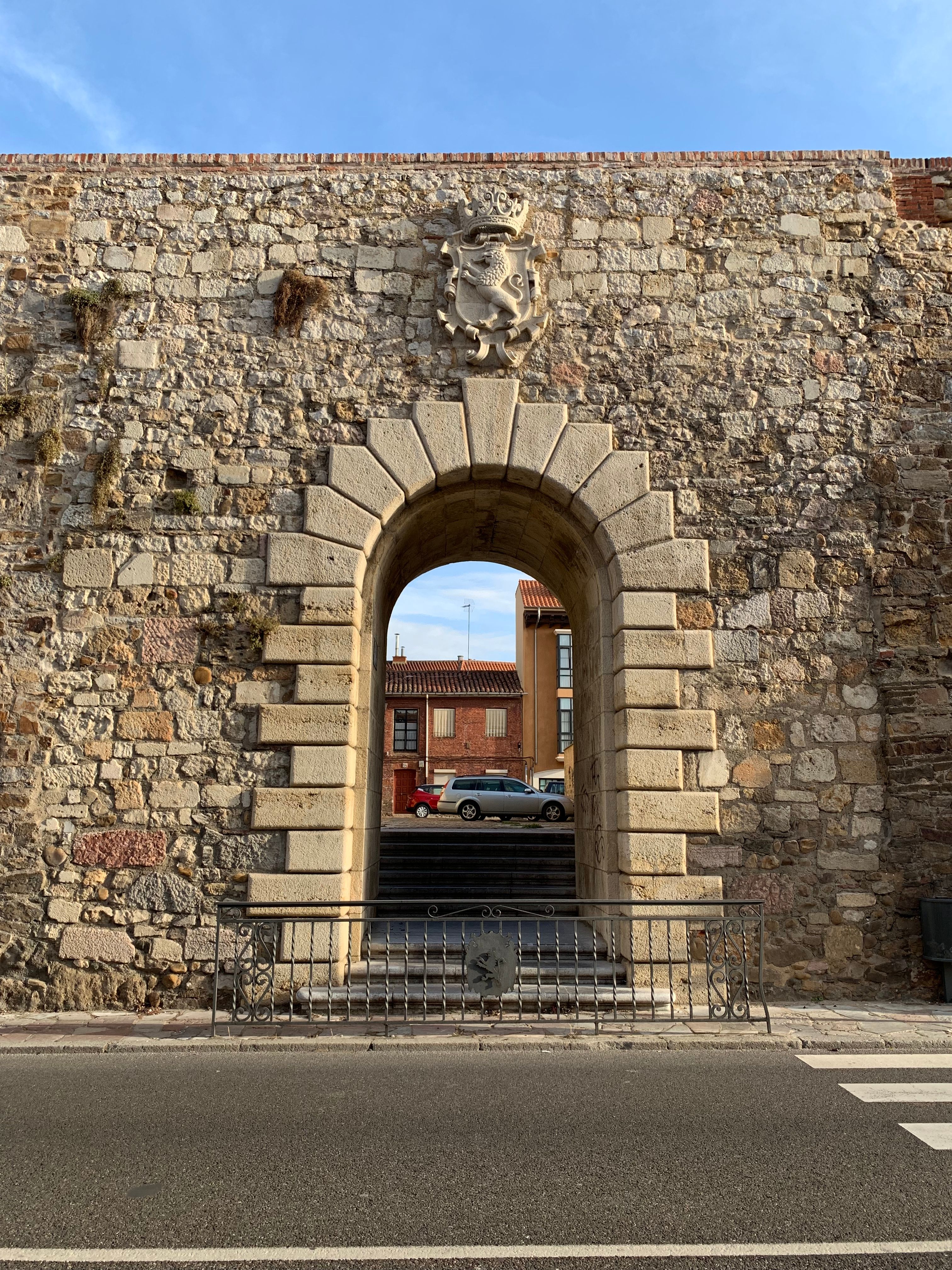 Ancient stone archway with coat of arms in León, Spain, captured on a sunny day.