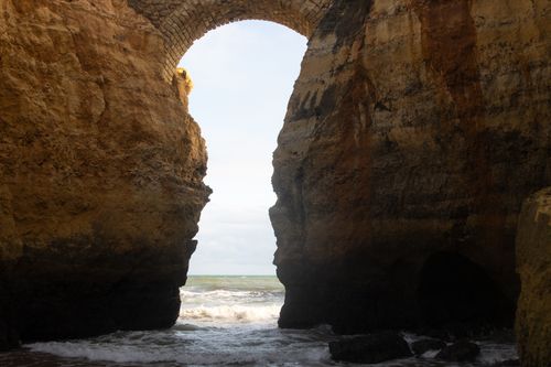 Free Breathtaking view of a natural arch formation on the Algarve coastline in Portugal, showcasing rugged cliffs and the Atlantic Ocean. Stock Photo