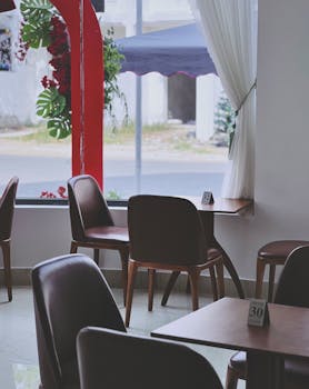 Quiet modern cafe interior featuring stylish chairs, tables, and a window view of the street.