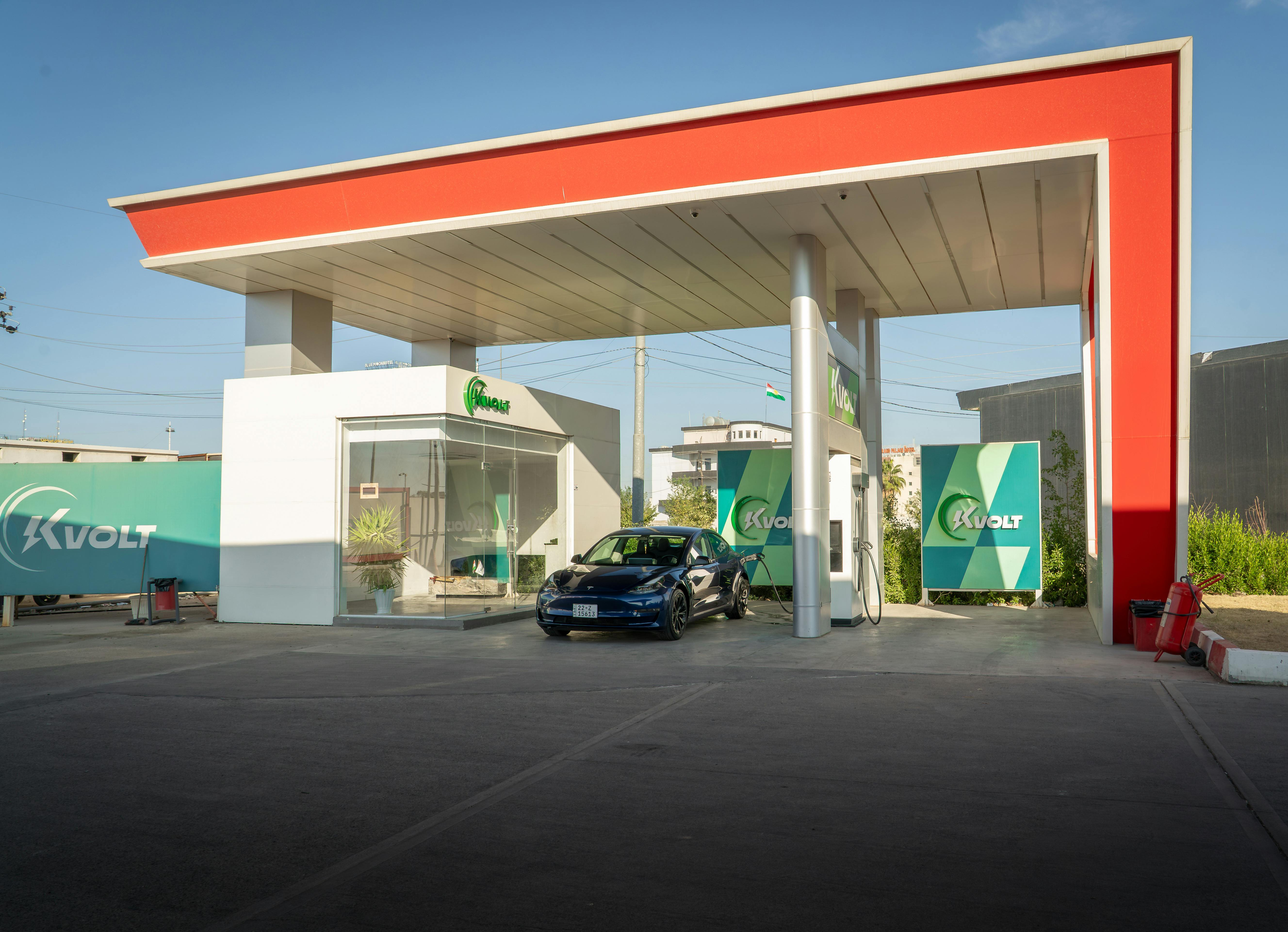 A sleek electric car charging at a modern station with blue skies in the background, promoting eco-friendly travel.