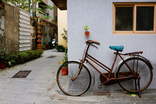 Free A vintage rusted bicycle leaning against a wall in a Taiwanese alley, highlighting urban charm. Stock Photo