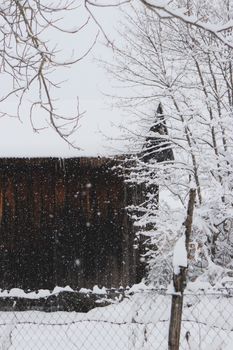 Serene snowy landscape featuring a rustic wooden barn and bare winter trees.
