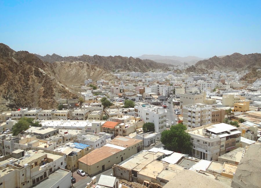 A stunning aerial view of Muscat, Oman, showcasing its unique architecture nestled between rugged mountains.