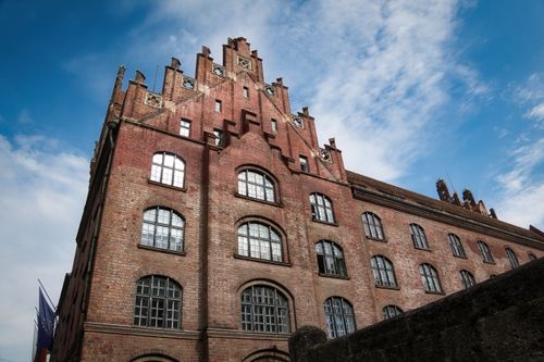 Free Architectural view of a historic brick building in Munich with a clear blue sky backdrop. Stock Photo