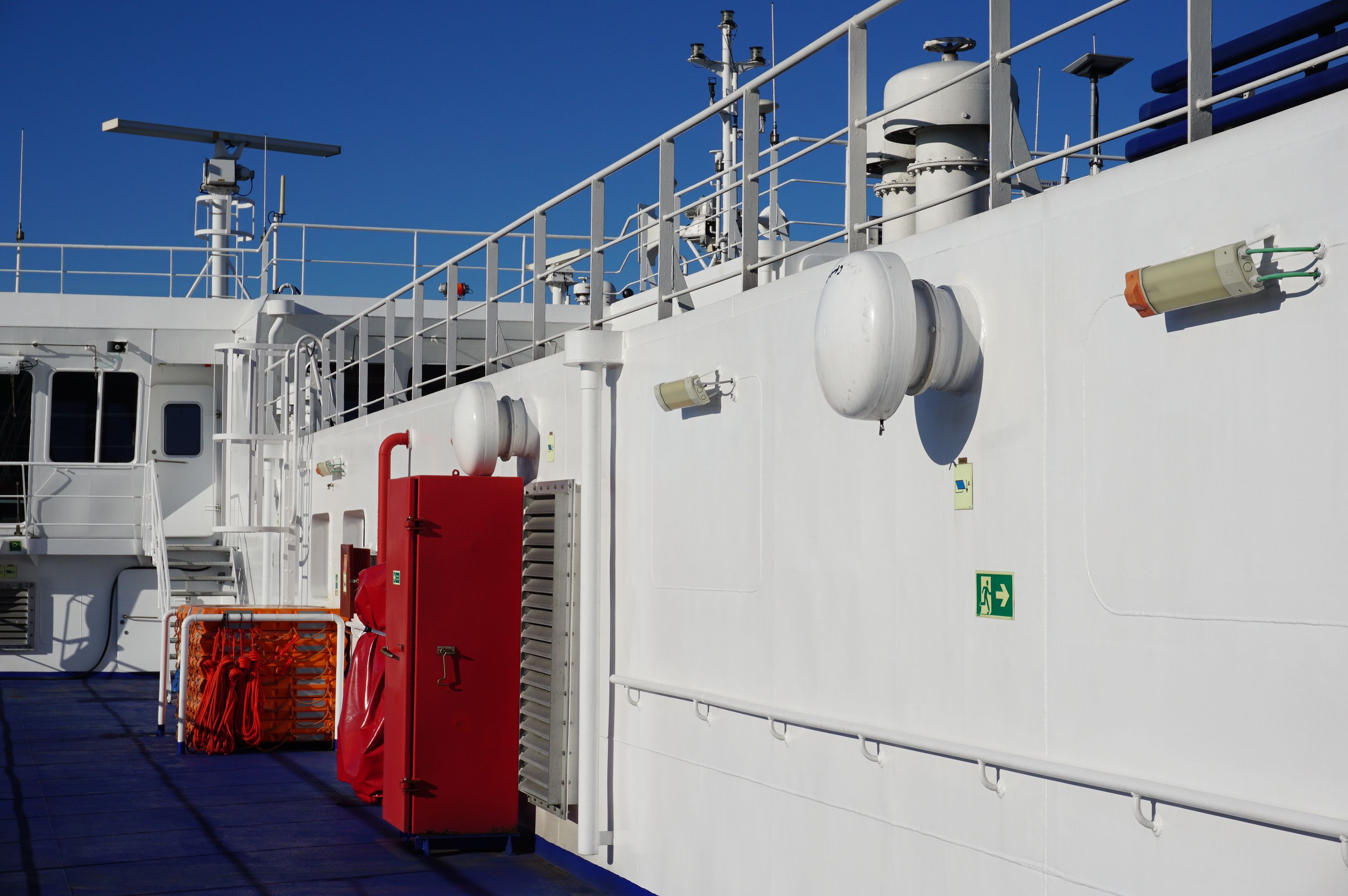A nautical scene depicting a ship deck with safety equipment under a bright, clear blue sky.