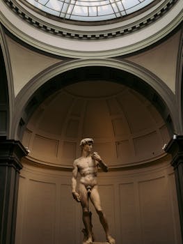 View of Michelangelo's David under a glass dome in Florence, highlighting classic Renaissance art.