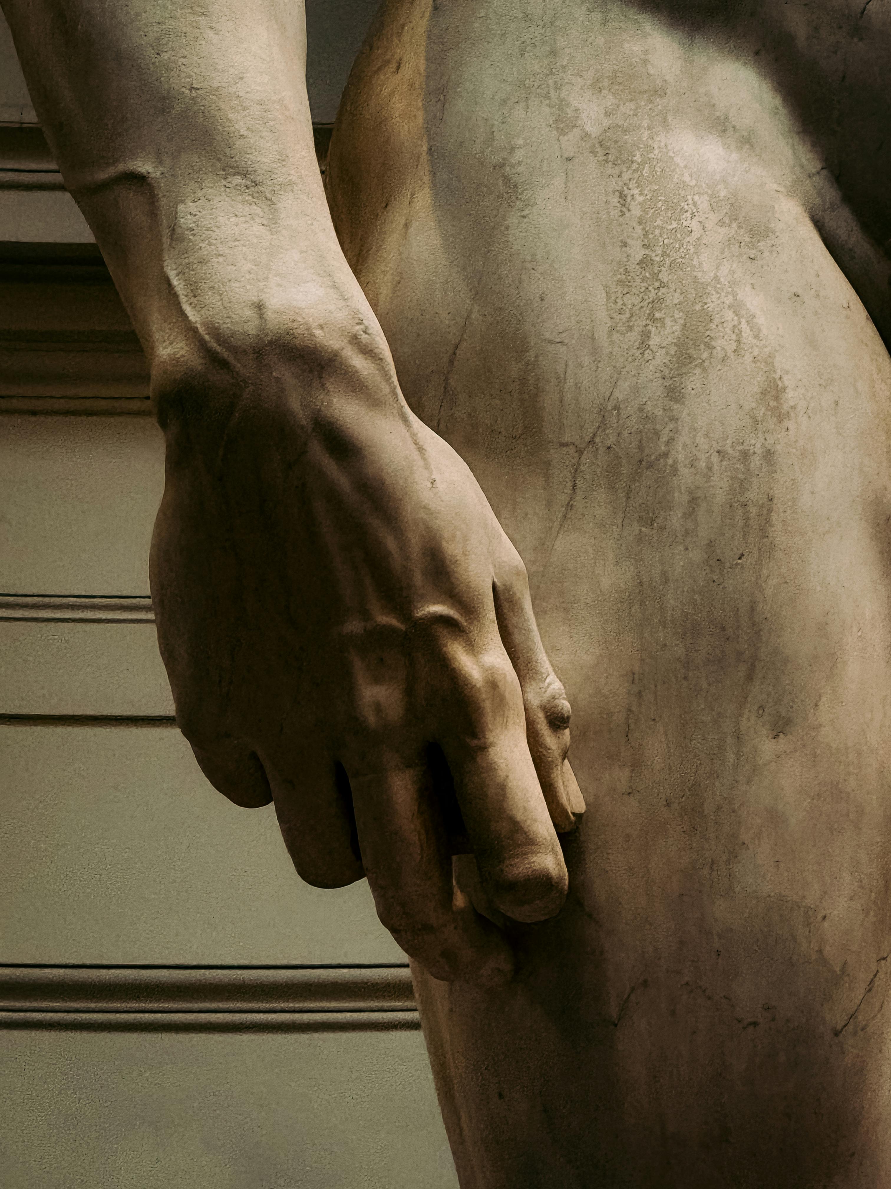 Detailed close-up of Michelangelo's David sculpture showcasing hand textures in Florence, Italy.