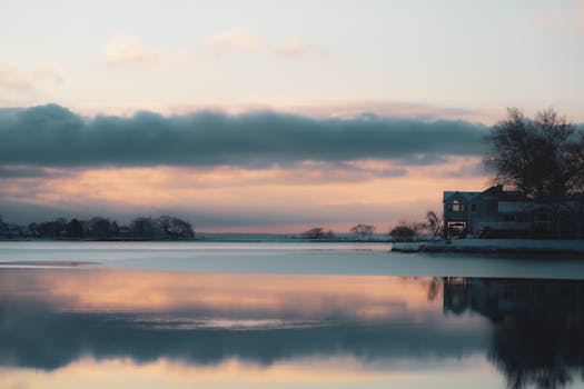 A peaceful winter sunrise over a tranquil lake with reflections.