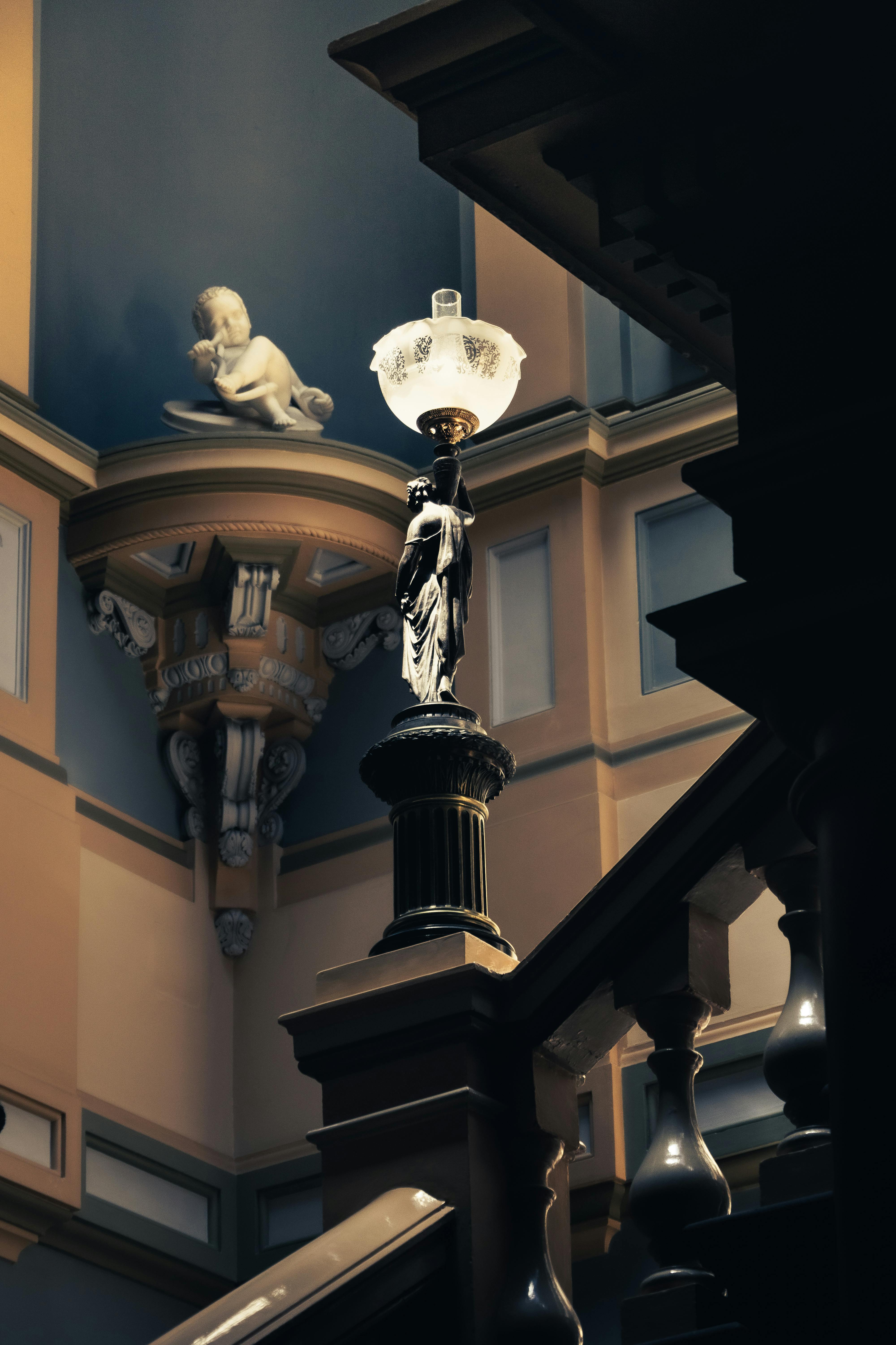 Gratuit Scenă interioară elegantă cu statui vintage și o lampă ornamentată pe o scară clasică Fotografie de stoc