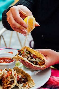 Close-up of a person squeezing lemon on tacos, enjoying a meal outdoors in Cuenca, Ecuador.