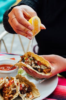 A close-up of flavorful tacos being garnished with lemon juice, capturing the essence of Ecuadorian street food.