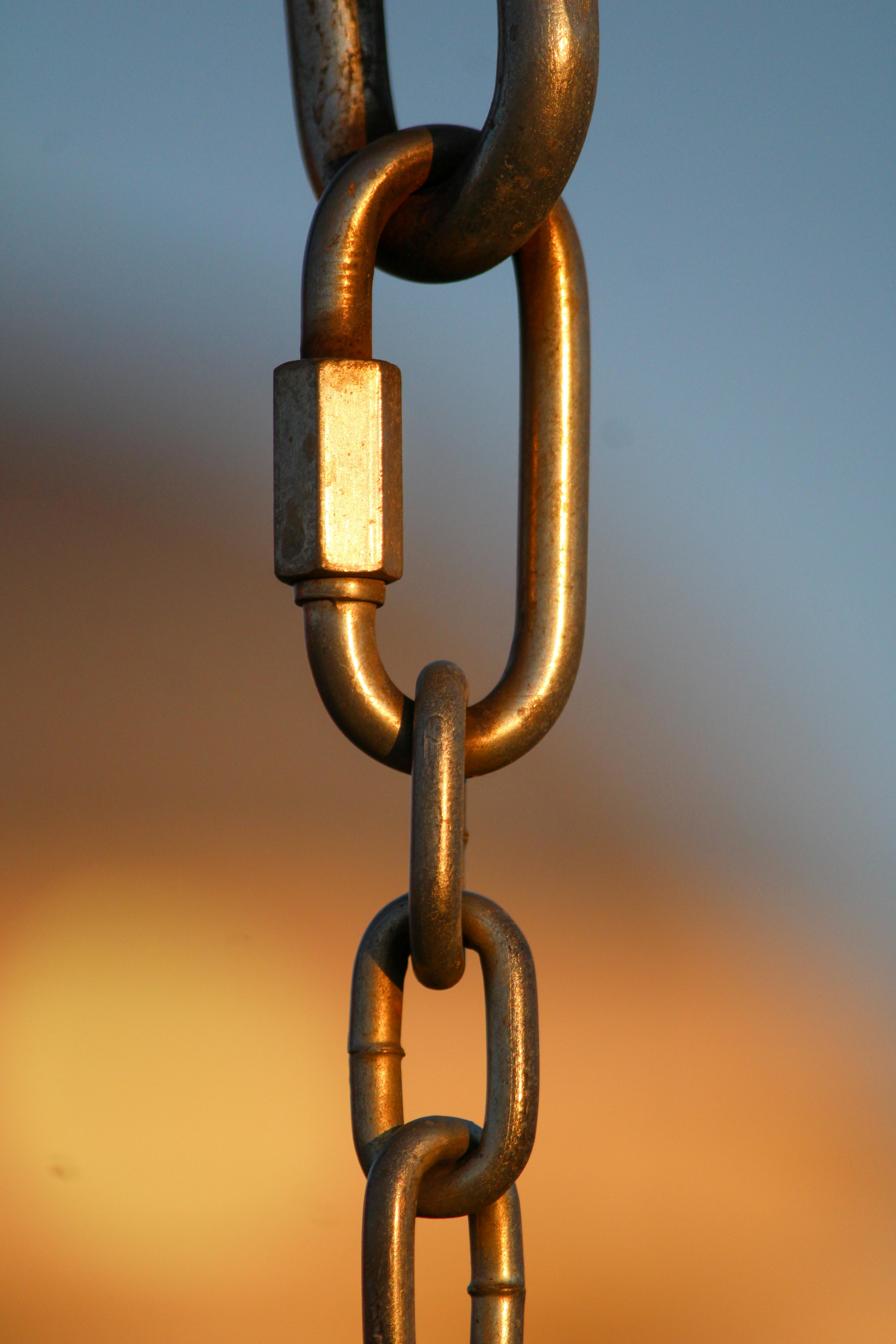 gratis Een gedetailleerd beeld van een metalen schakel tegen een wazige achtergrond, waarbij de nadruk ligt op sterkte en verbinding. Stockfoto