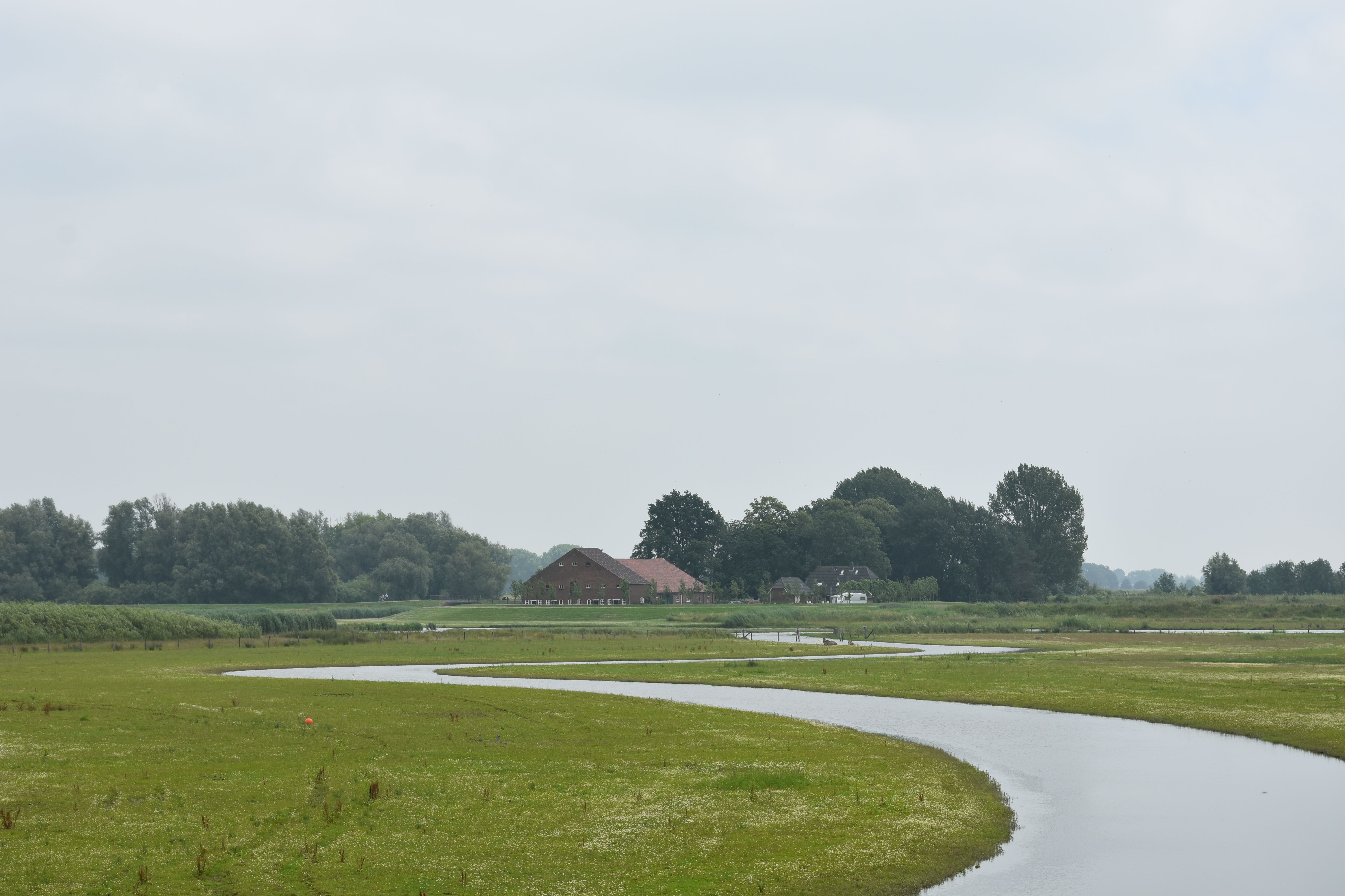 A tranquil rural scene featuring a winding river and distant farmhouse, ideal for nature lovers.