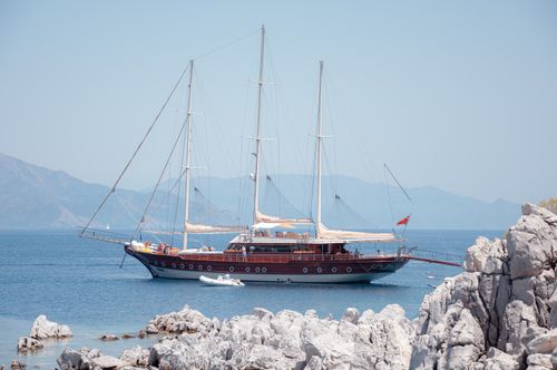 Free Elegant yacht moored in Marmaris with scenic rocky coastline and clear blue sea, ideal for travel and adventure. Stock Photo