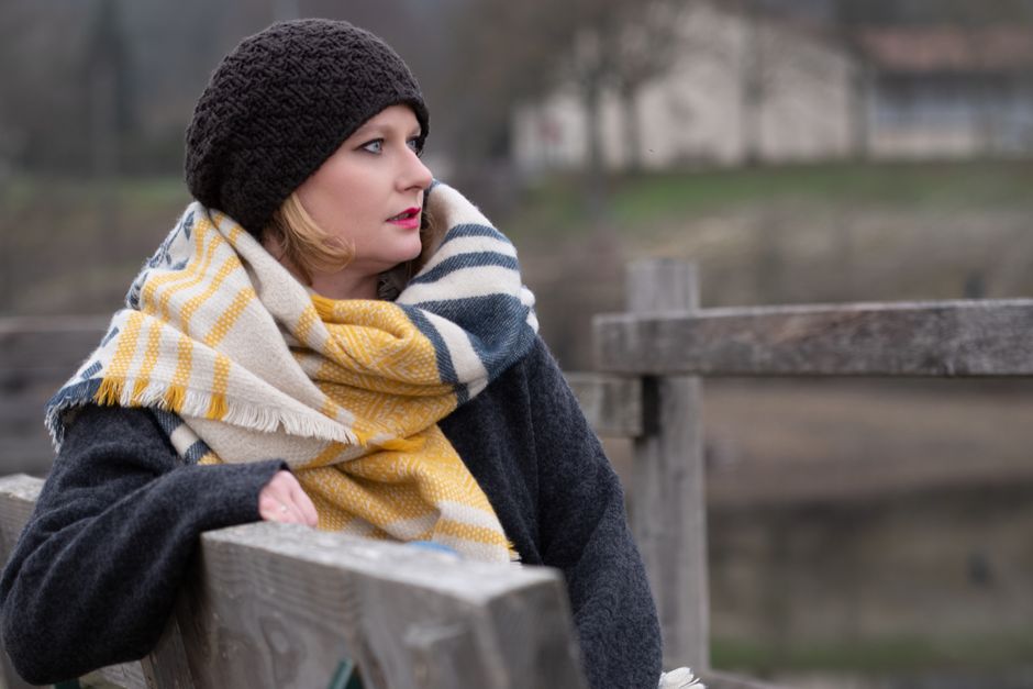 Stylish woman in warm winter attire enjoys a peaceful moment on a bench in Lyon, France.