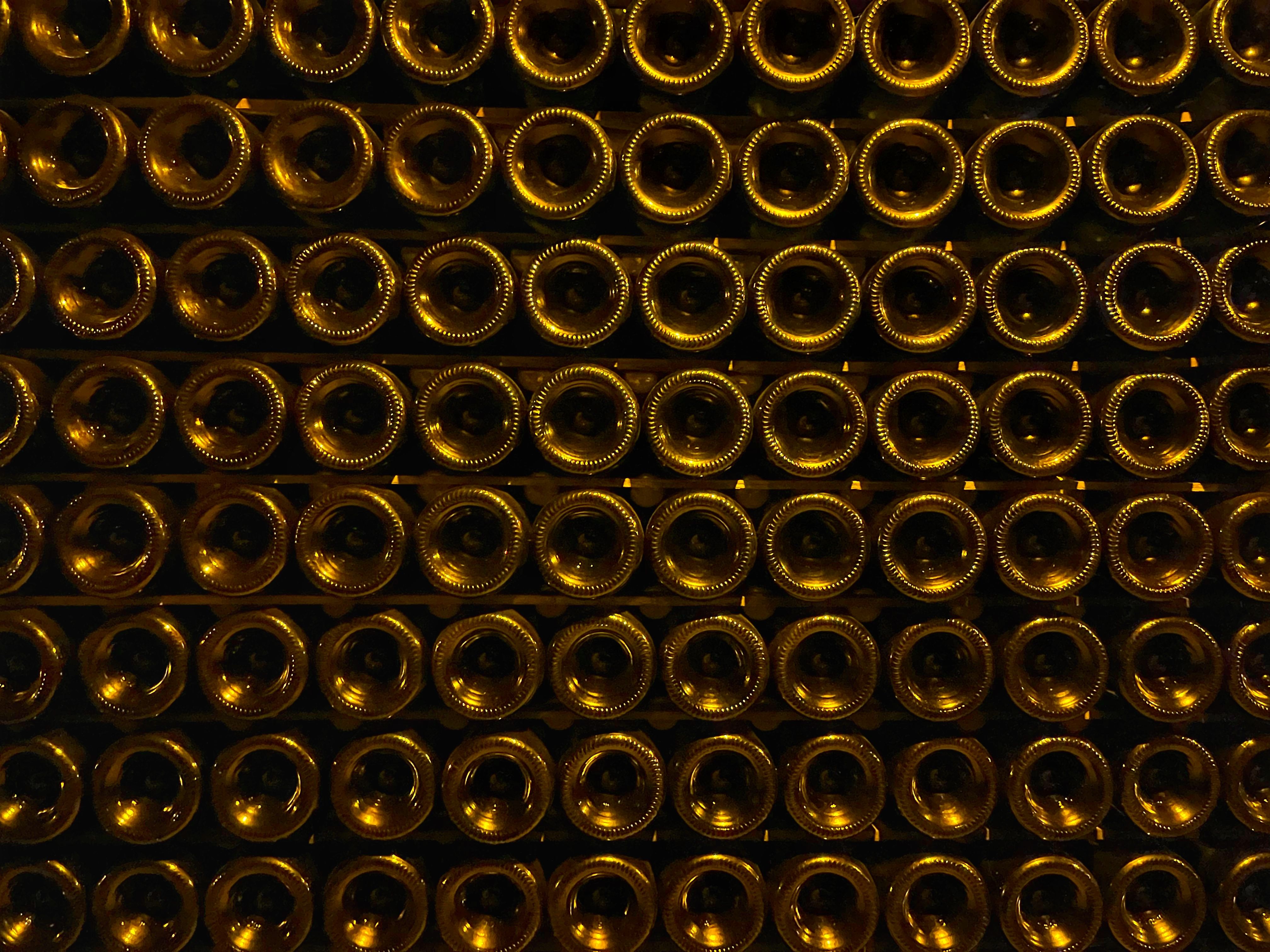 Rows of stacked wine bottles in a dimly lit cellar with elegant symmetry and warm tones. Rows of stacked wine bottles in a dimly lit cellar with elegant symmetry and warm tones.