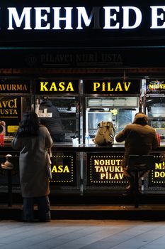 People dining at a traditional Turkish street food stall in Istanbul at night.