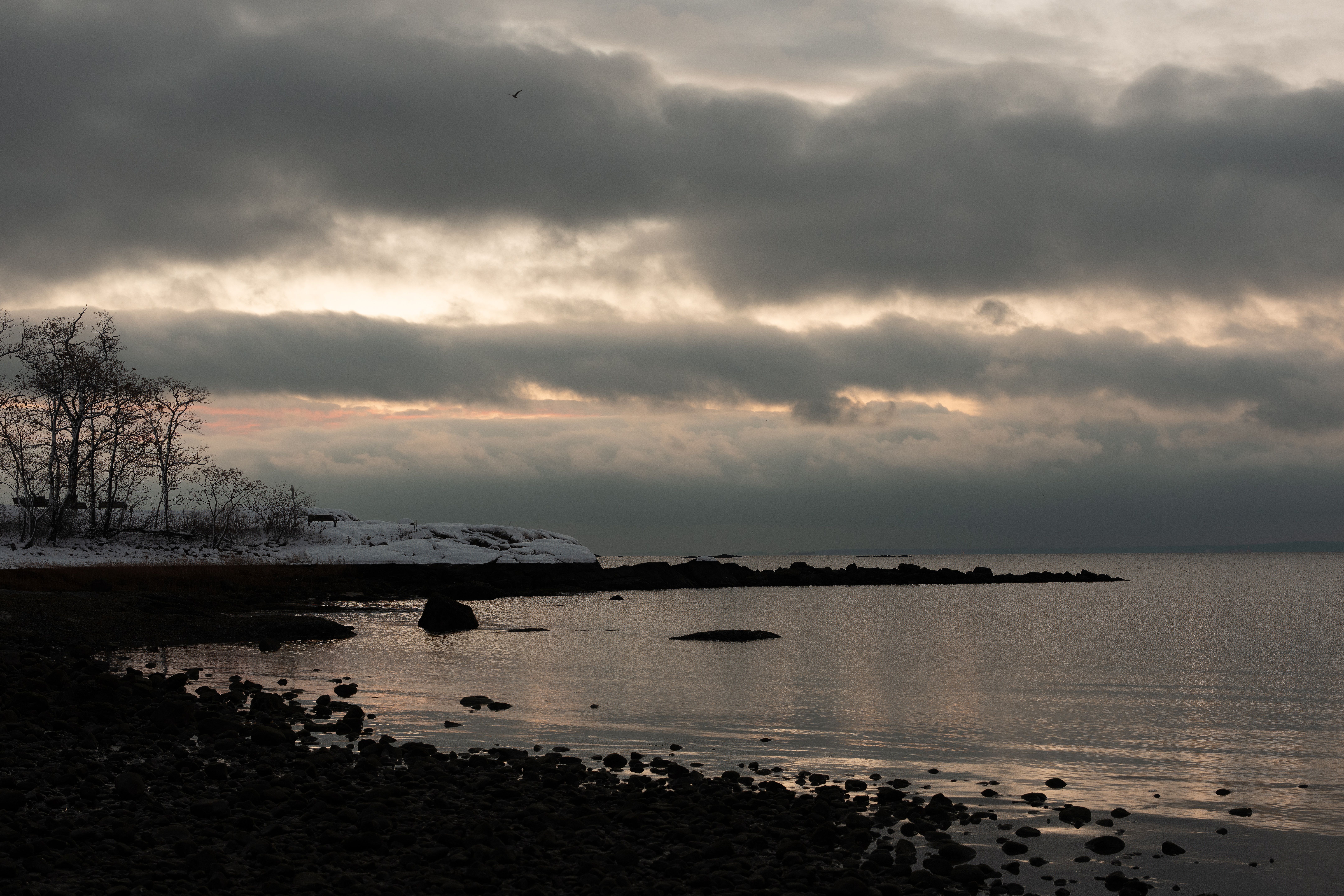 Serene winter sunrise over water at Cove Island Park, Stamford, Connecticut, with dramatic clouds.