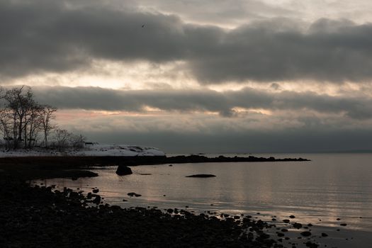 Serene winter sunrise over water at Cove Island Park, Stamford, Connecticut, with dramatic clouds.