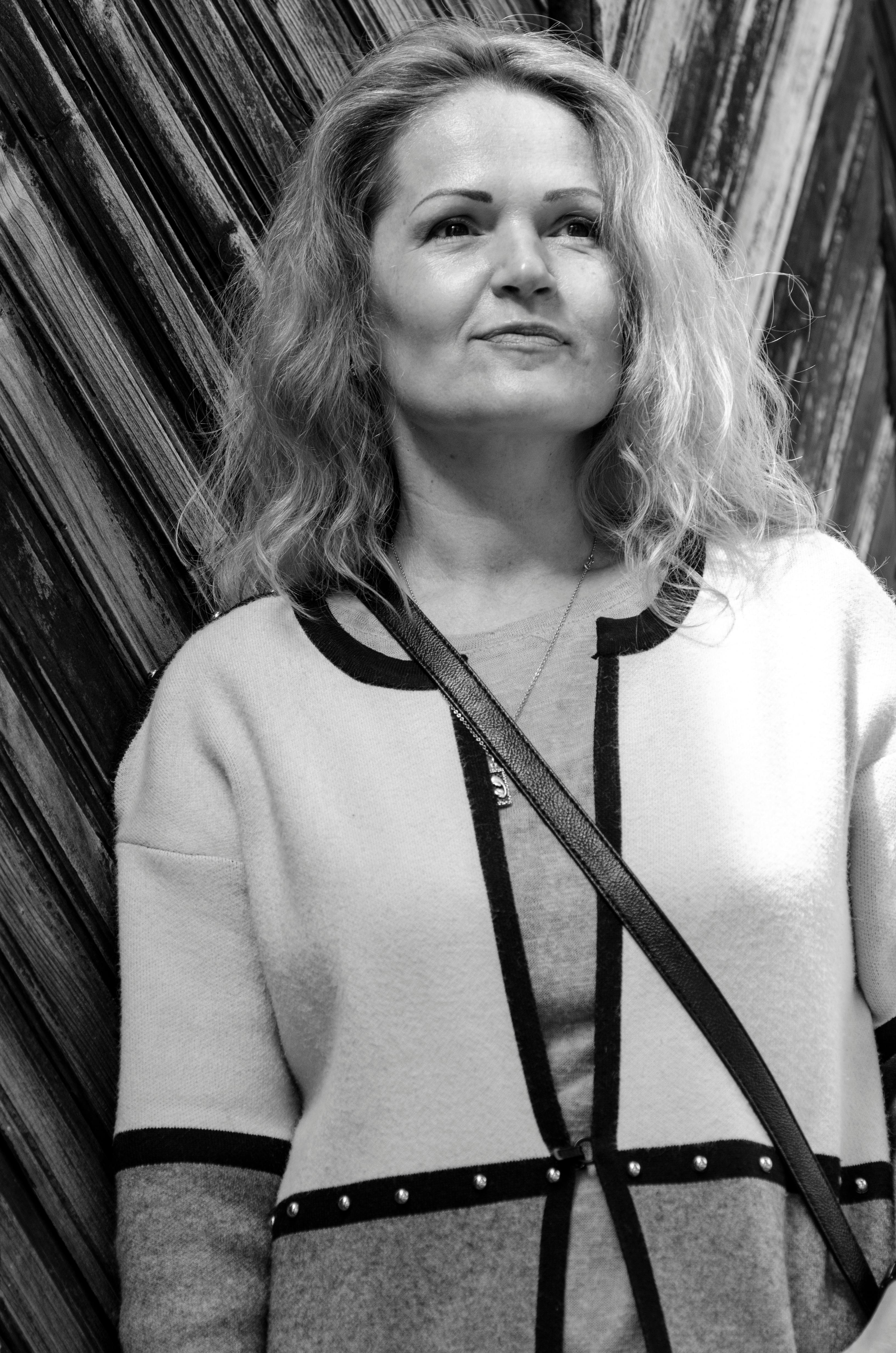 Black and white portrait of a confident woman standing against a textured wooden background in Lviv.