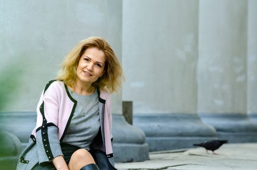 Woman sitting outdoors by classical columns in Lviv, Ukraine. Relaxed and elegant.