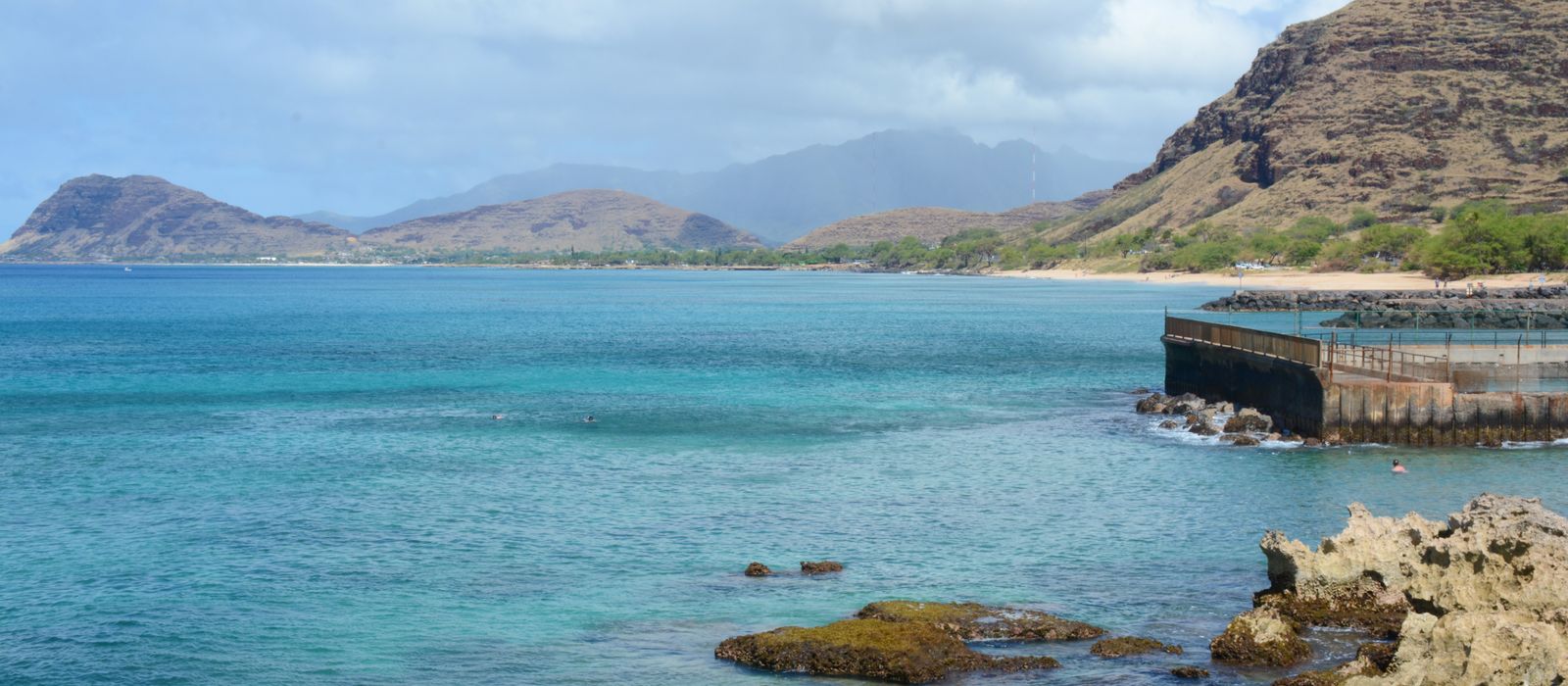 Panoramic view of a tranquil coastline with rock formations and clear waters in Kapolei, Hawaii.
