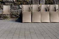 Wicker outdoor chairs arranged against a rustic stone wall in Lviv, Ukraine.