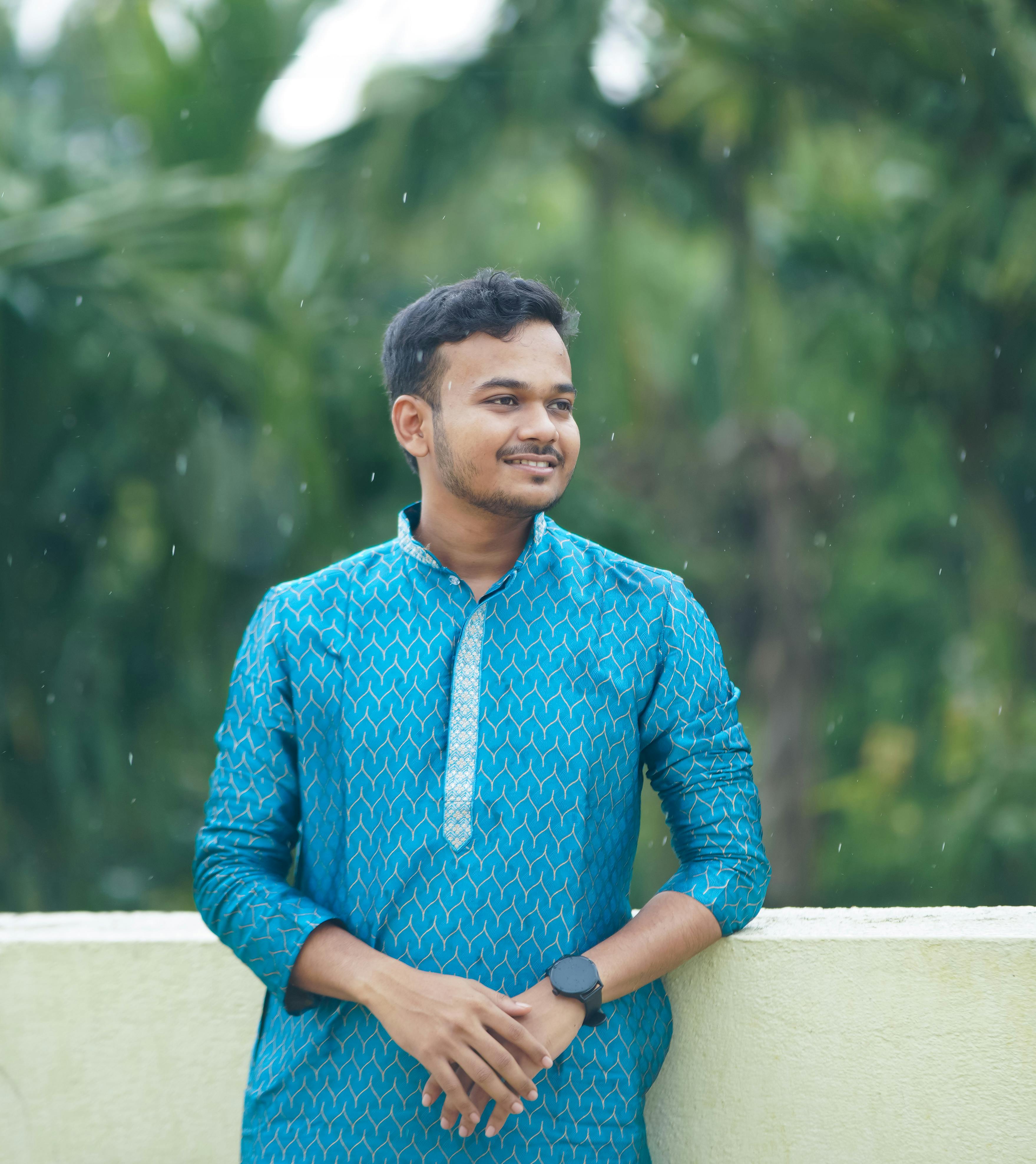 Happy young man wearing a blue traditional outfit, enjoying the outdoors on a rainy day.