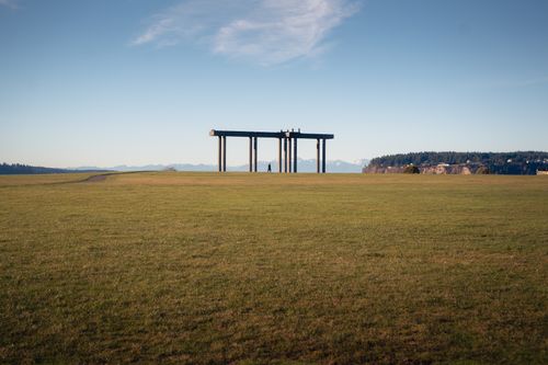 Free Person walking near large steel beams in open field with clear sky. Stock Photo