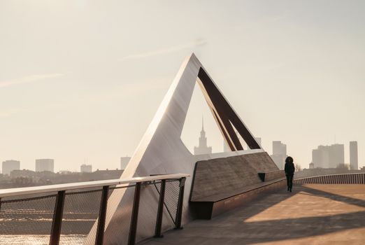 A striking modern structure in Warsaw's cityscape with a person walking nearby.