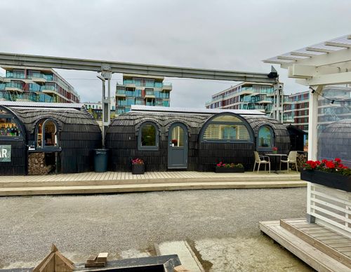 Free Unique wooden cabins with outdoor seating in Tallinn, Estonia, set against modern architecture. Stock Photo