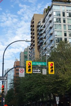 Downtown Vancouver street scene with Drake St sign, traffic lights, and modern buildings.