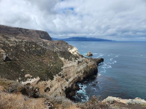 Scenic view of rugged cliffs along the California coastline under a cloudy sky.