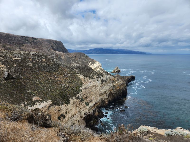 Scenic view of rugged cliffs along the California coastline under a cloudy sky.