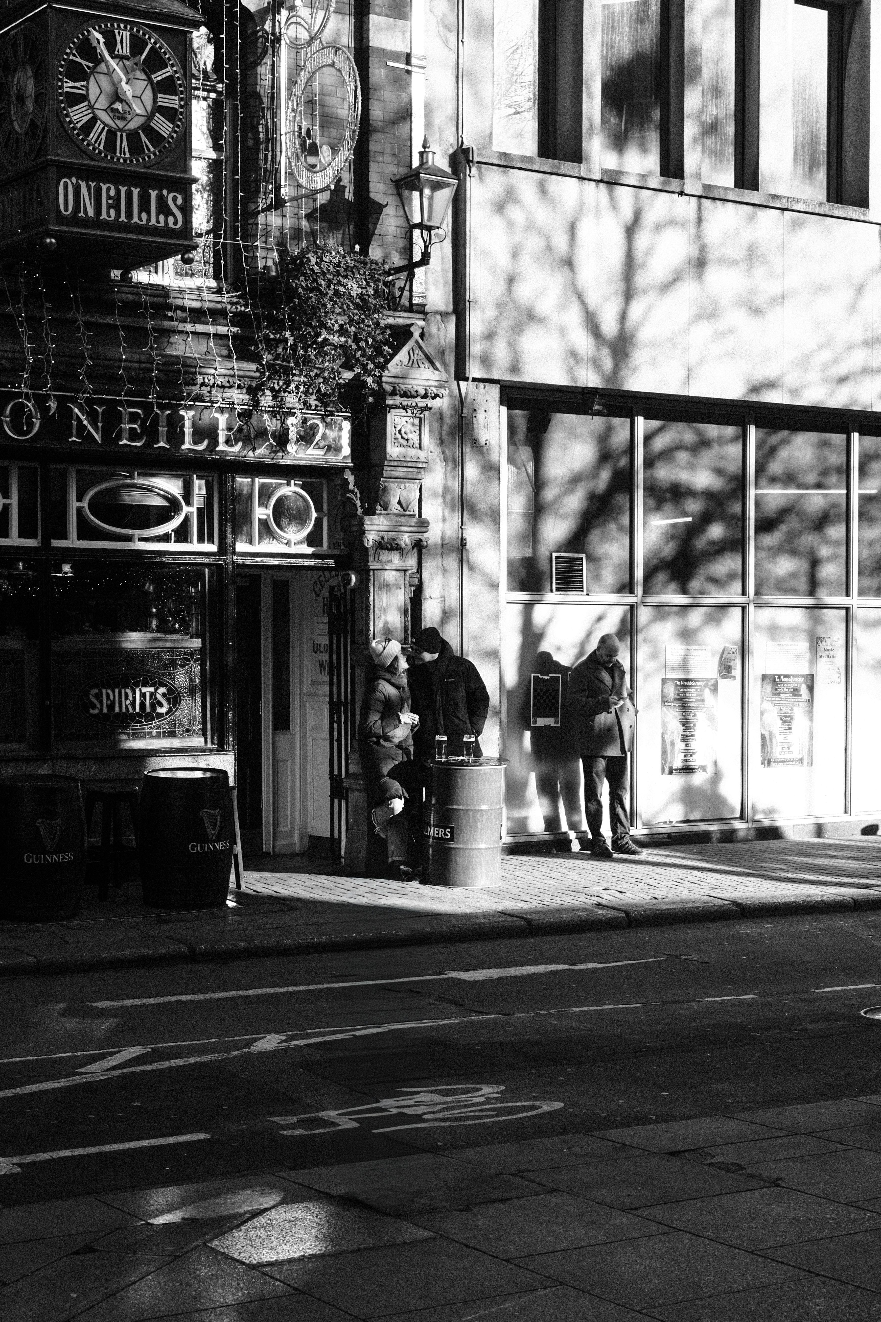 Monochrome photograph capturing urban life outside a traditional Irish pub in Dublin.