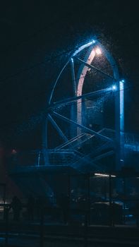 A strikingly illuminated modern architectural structure under a snowy night sky, creating a serene winter atmosphere.