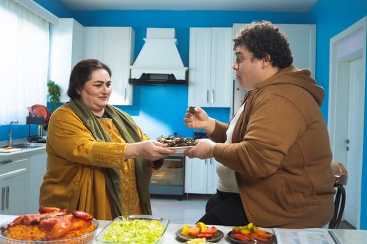 A warm moment of a mother and son enjoying a delicious traditional meal together in a cozy kitchen.