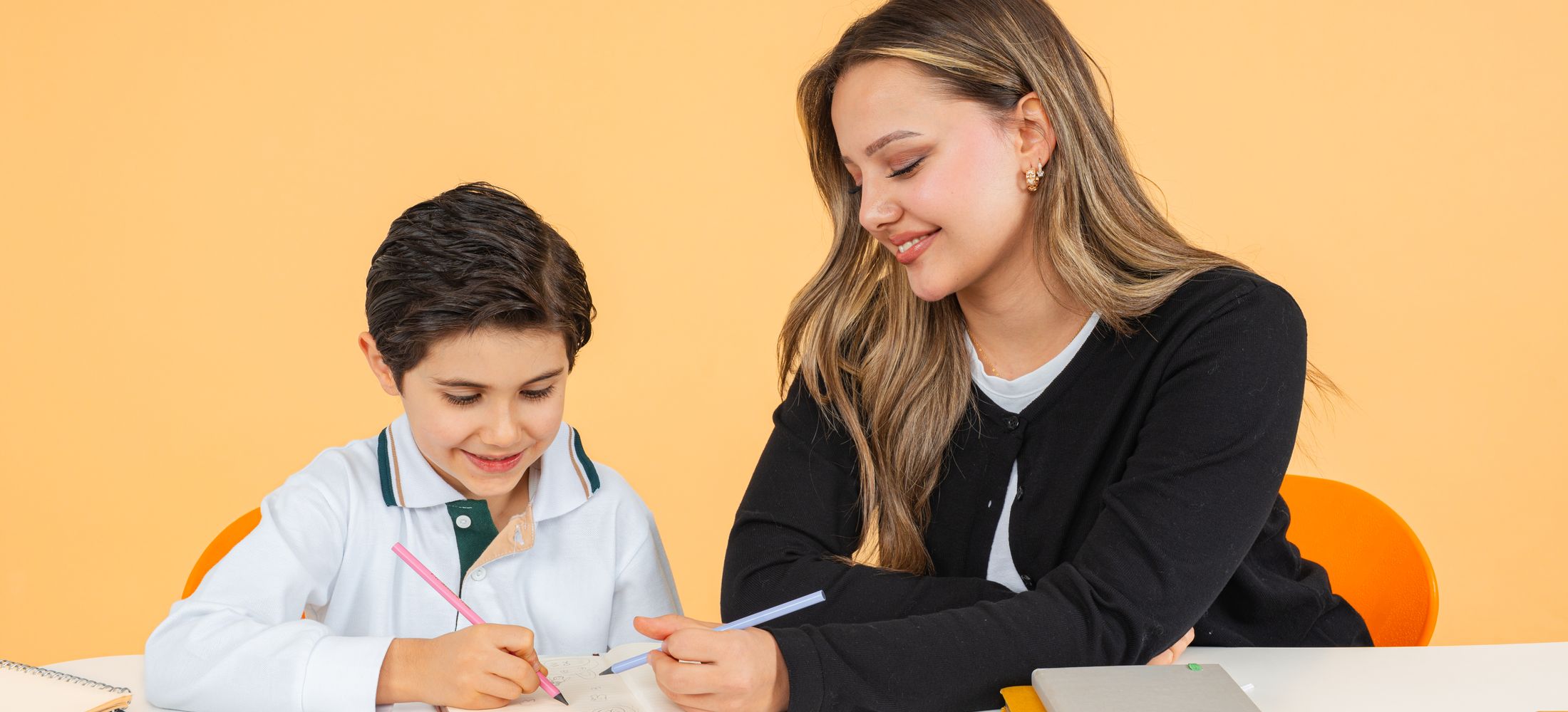 Teacher supporting a child with writing in a classroom