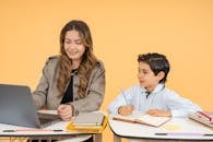 Teacher Assisting Student with Homework on Laptop