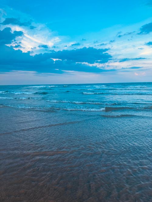 Free Peaceful ocean waves gently lapping at the shore under a dramatic blue sky. Stock Photo