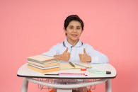 Smiling Schoolboy with Thumbs Up at Desk