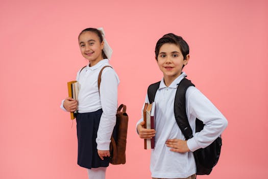 Two happy students posing with books and backpacks against a pink background.