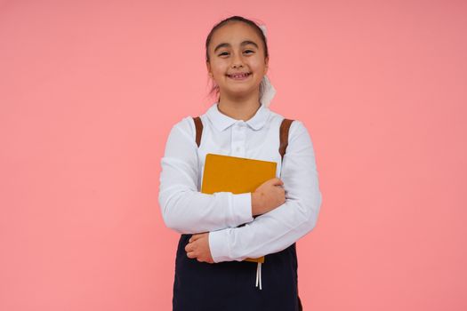 A cheerful schoolgirl holding a book against a bright pink background, symbolizing education.