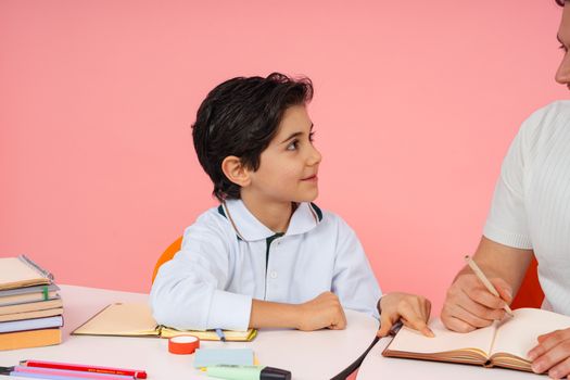 A young student interacts with an adult while studying together indoors at school.